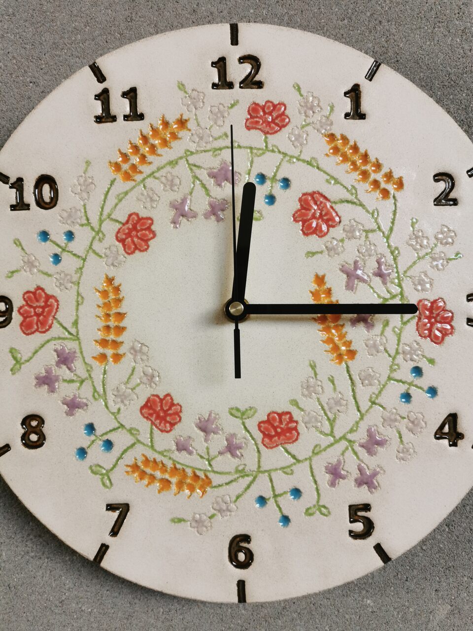 zbliżenie na tarczę zegara ceramicznego z motywem kwiatów