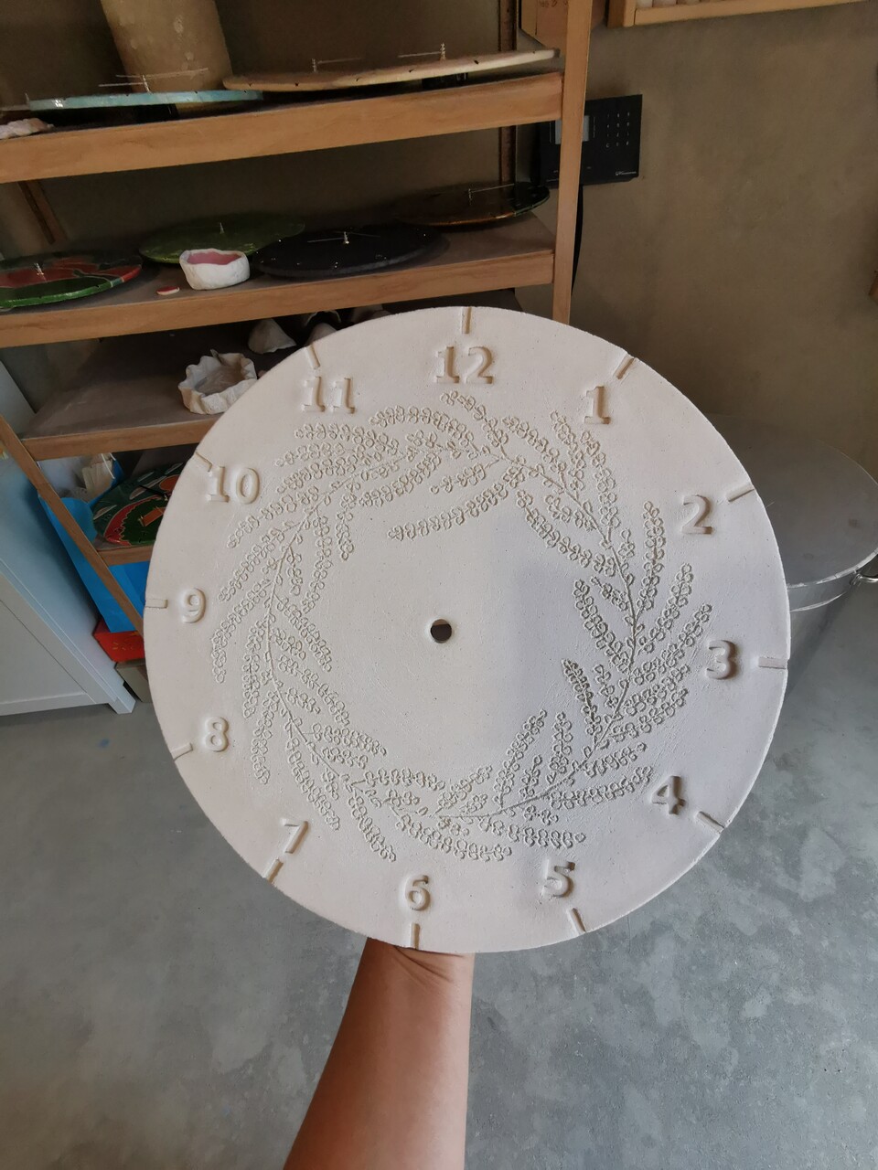 Ceramiczna tarcza zegara na tle pracowni ceramicznej Eweolo