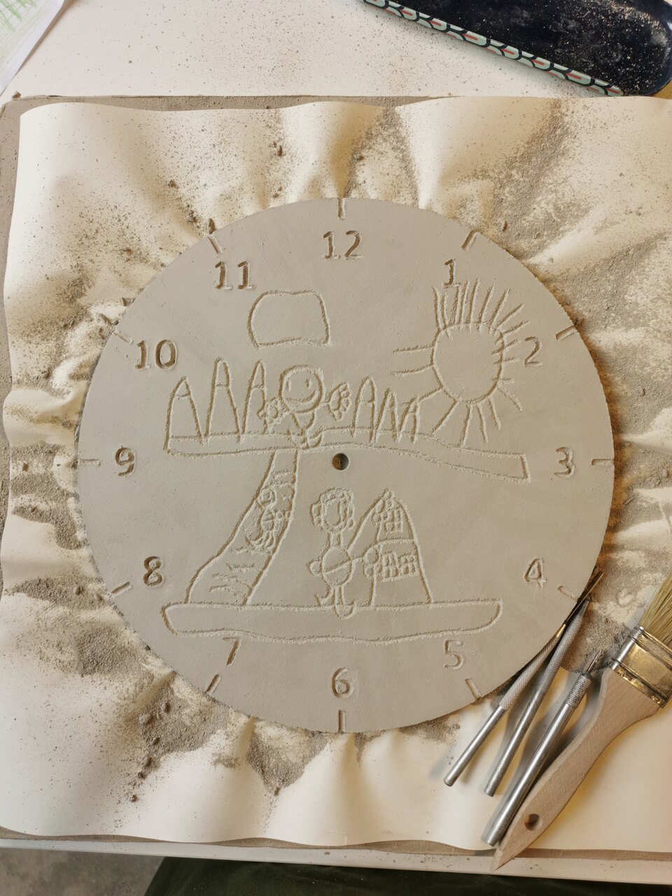proces przenoszenia rysunku dziecka na glinę, ręcznie lepiony zegar ceramiczny w pracowni eweolo