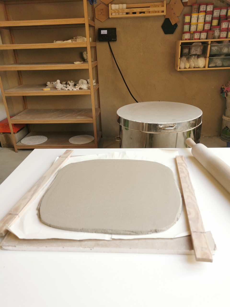 kawałek gliny na stole w pracowni ceramicznej w tle piec ceramiczny