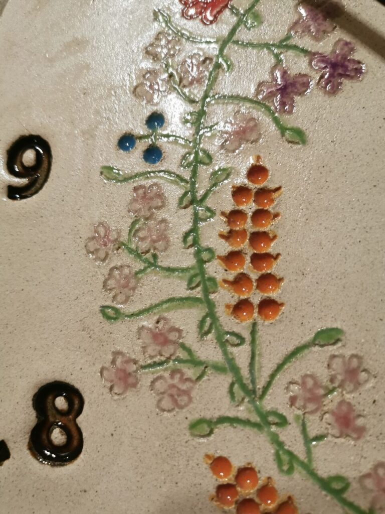 detal na zegarze przedstawiający kłos zboża i niezapominajki