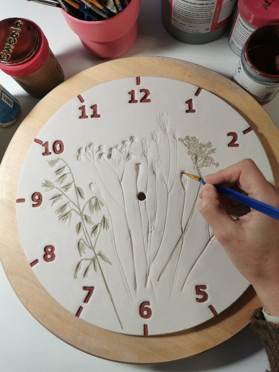 szkliwienie tarczy ceramicznego zegara pędzlem - rękodzieło na zamówienie