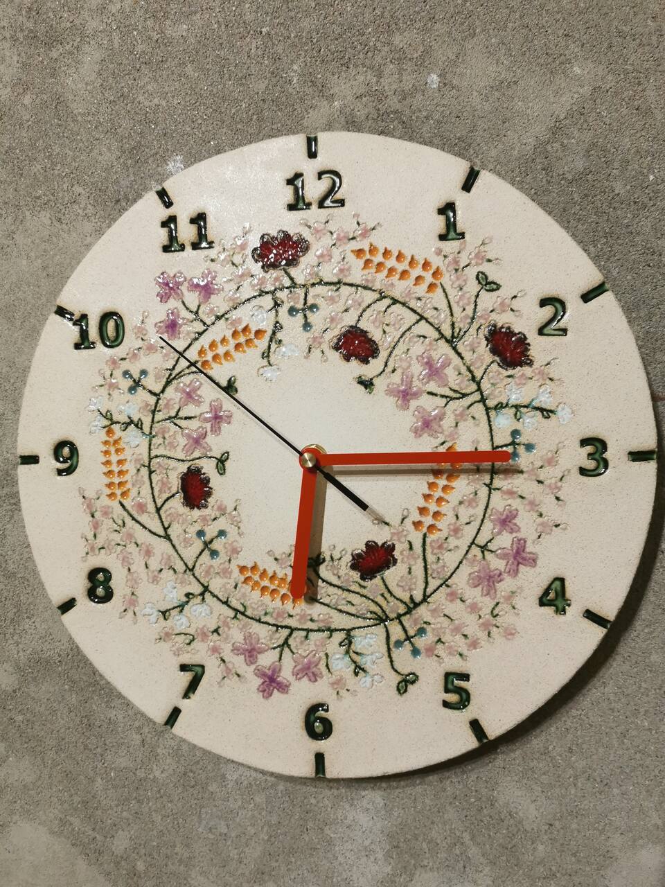 Ceramiczny zegar na betonowej ścianie, dodaje uroku i lekkości wnętrzu.