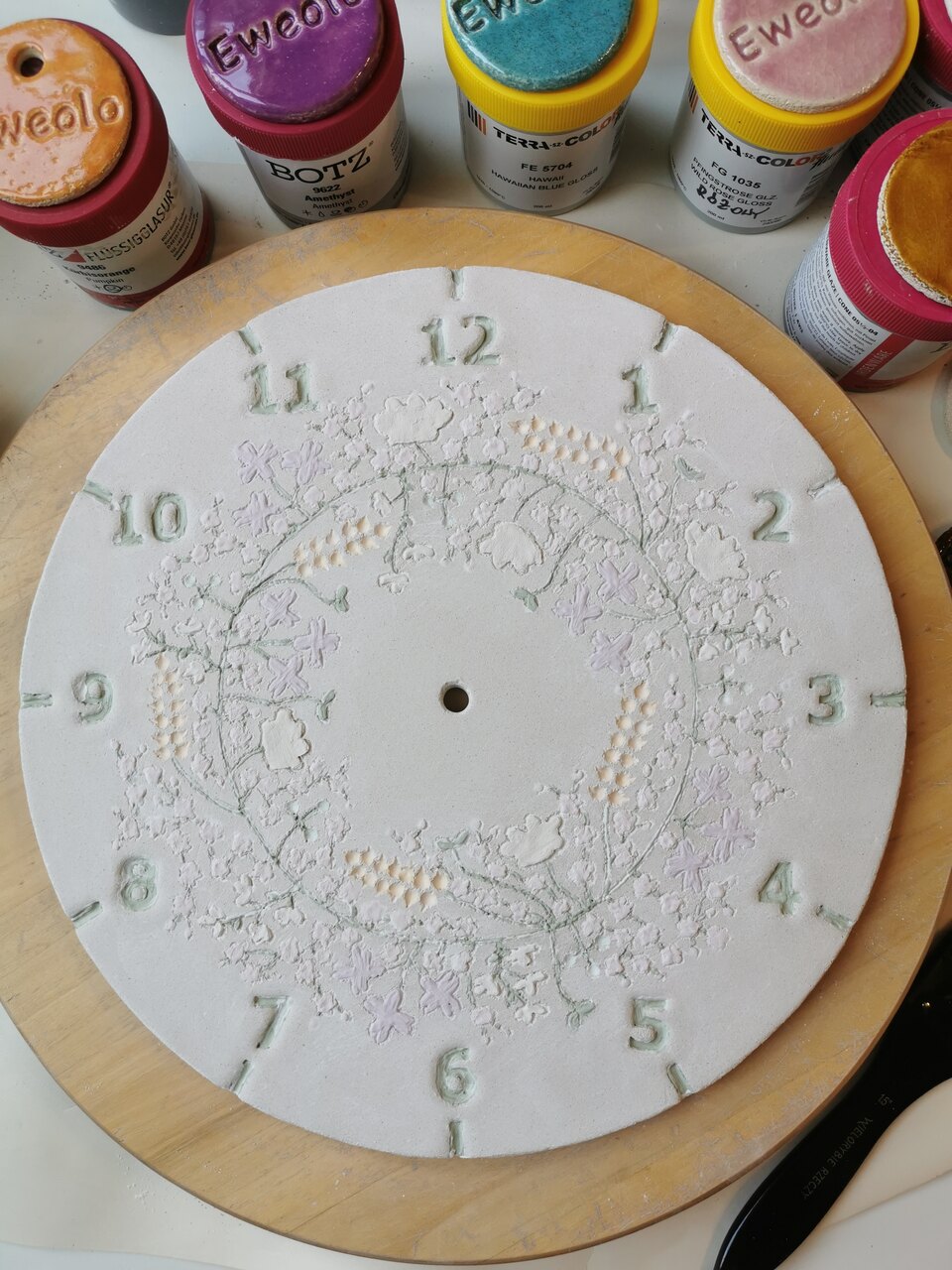 Ceramiczny zegar kwietny z nałożonym szkliwem przed finałowym wypałem.