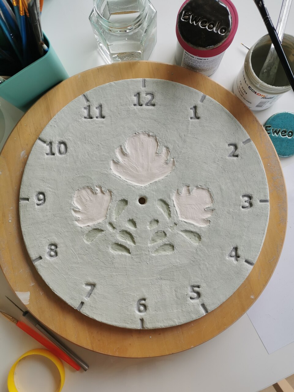 Tarcza ściennego zegara w pracowni na stole gotowa do wypału.