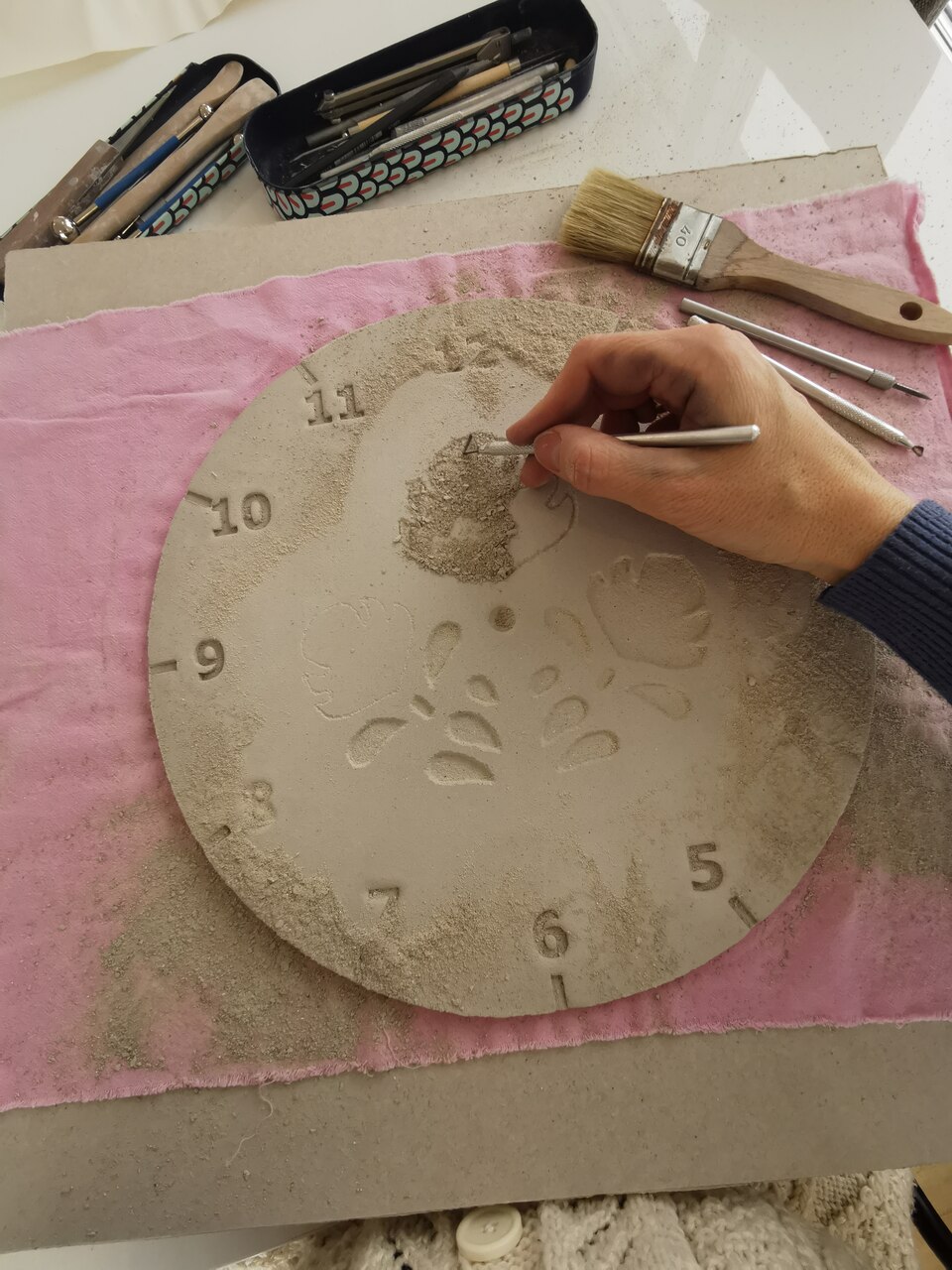 Ręczne wycinanie tradycyjnych motywów roślinnych na ceramicznym zegarze eweolo.