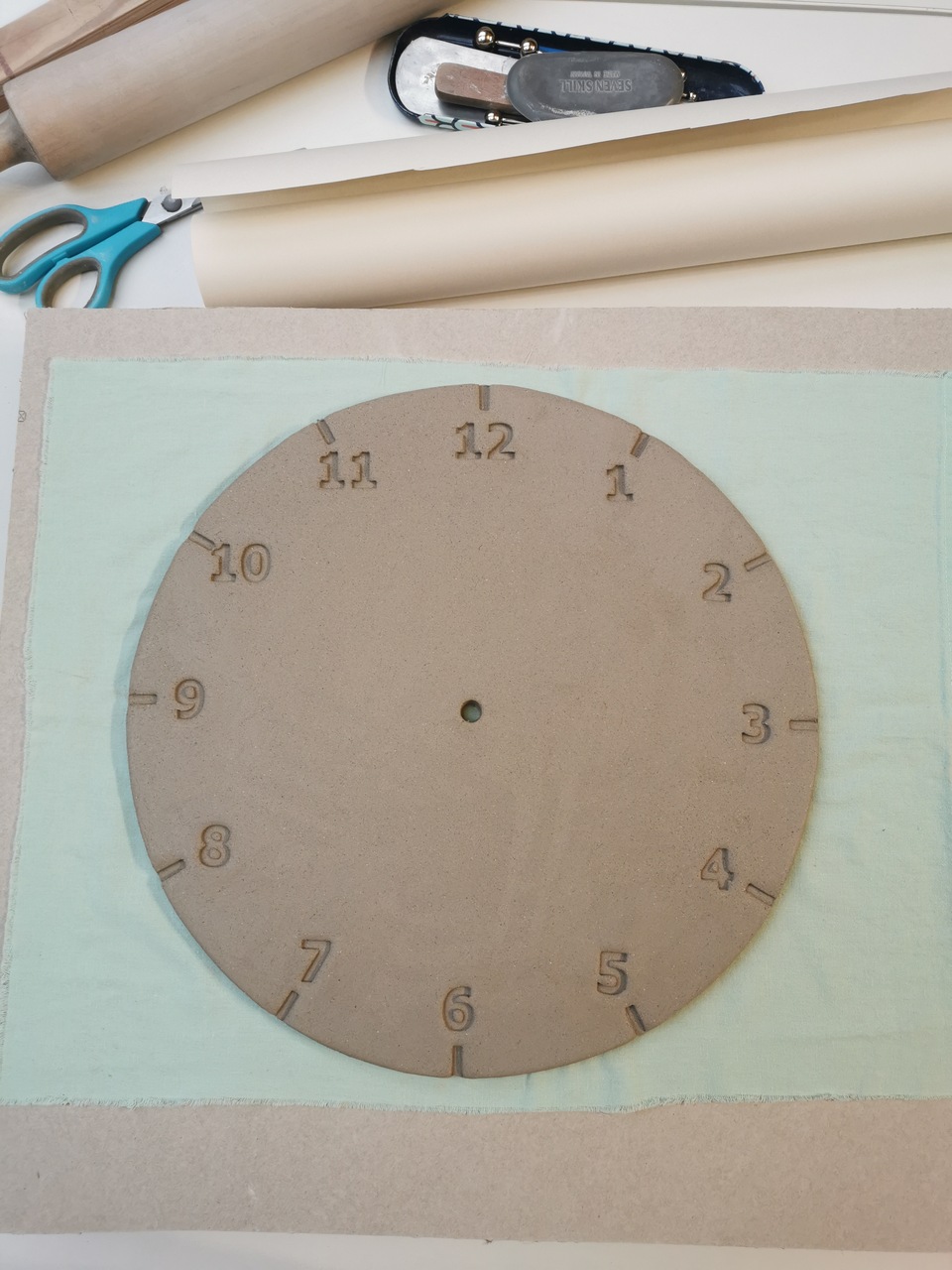 Gliniana tarcza zegara czekająca na ręcznie wykonany wzór kwiatowy.