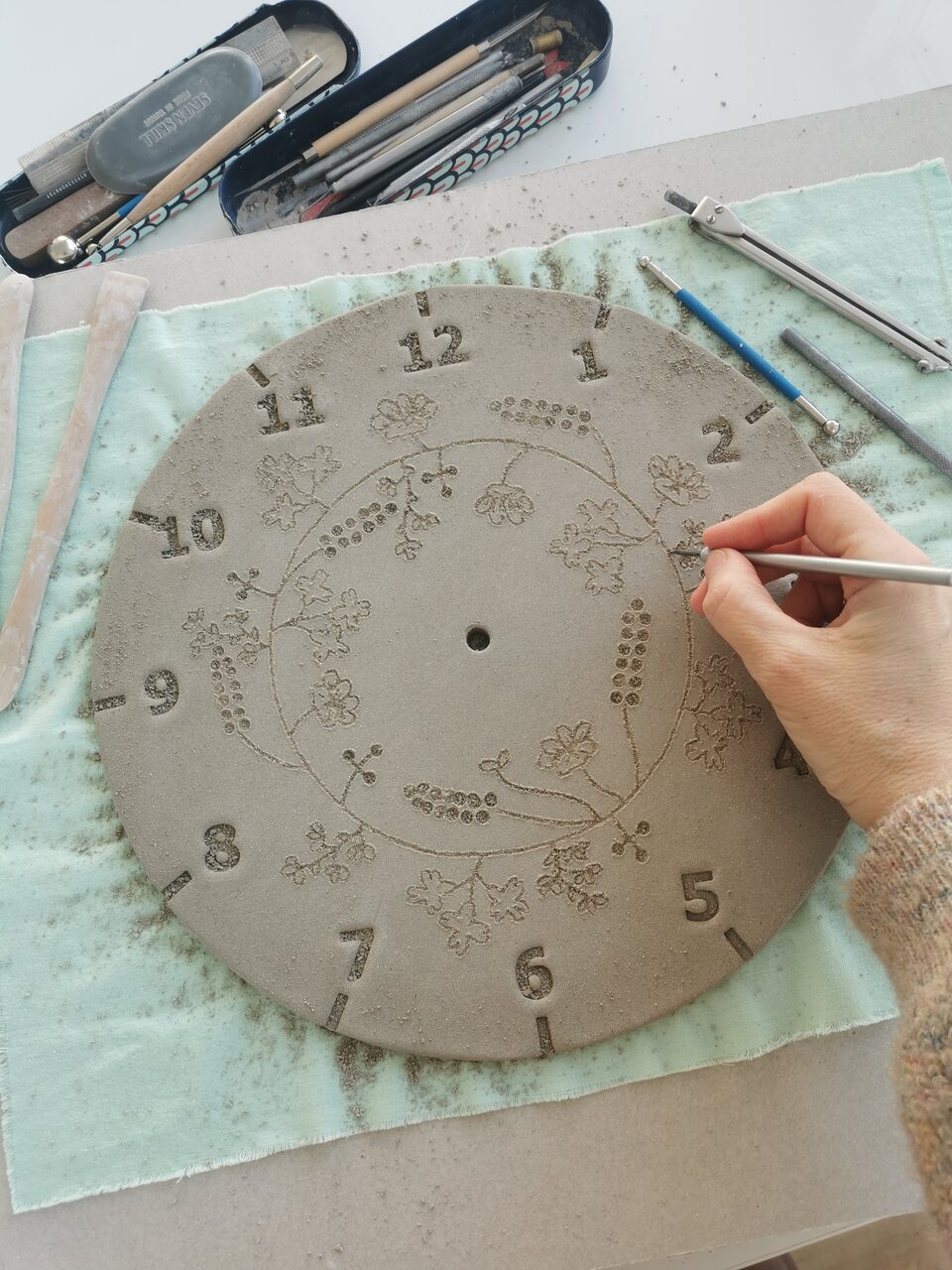 Etap formowania płatków i detali roślinnych podczas pracy nad zegarem kwietnym.