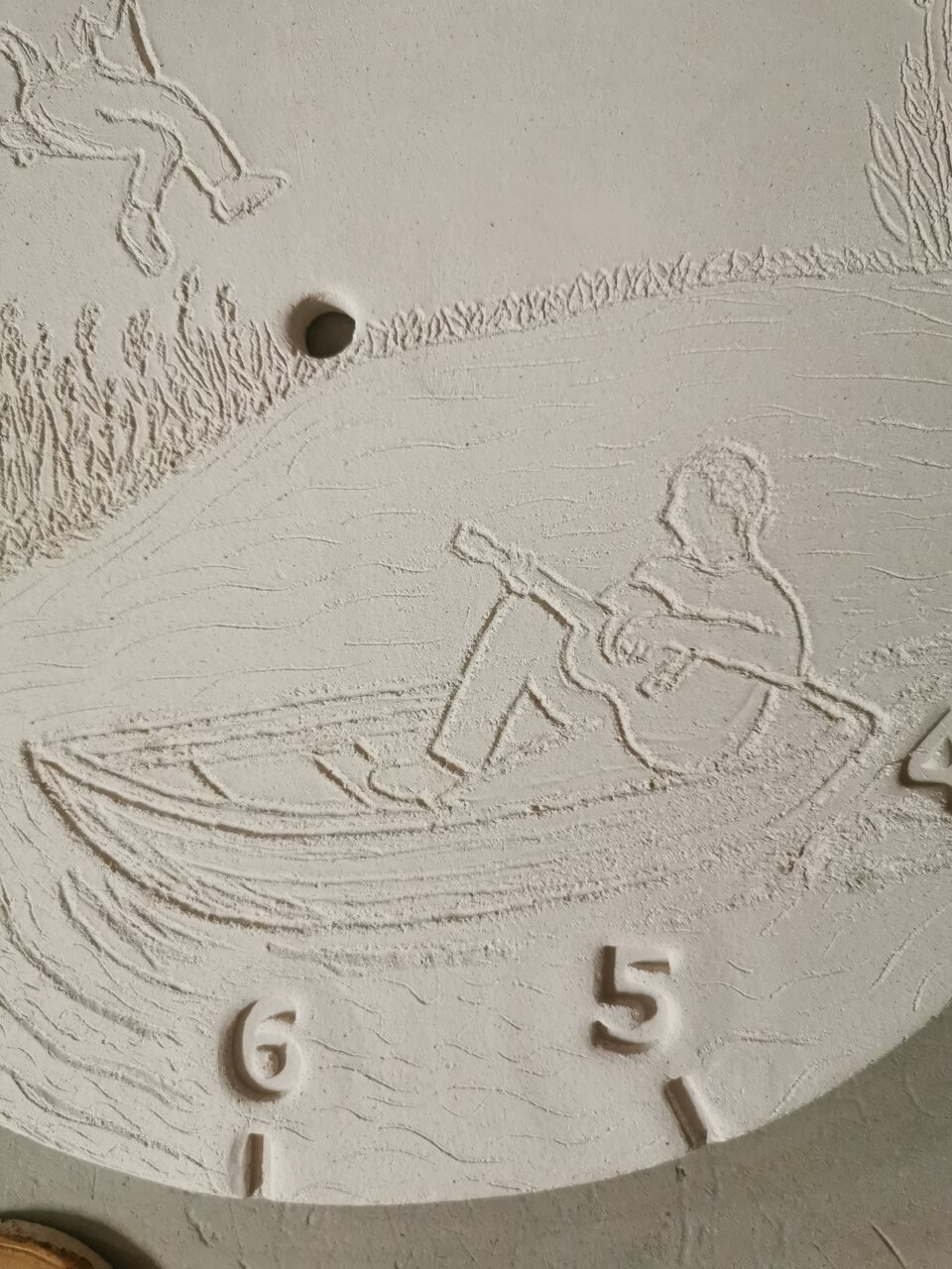 Najazd na detal na ceramicznym zegarze na prezent na rocznicę ślubu - tata w łódce na środku jeziora gra na gitarze