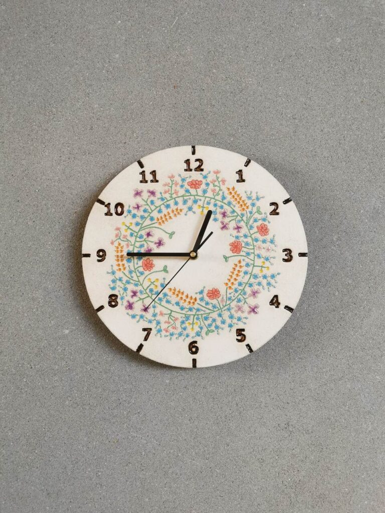 Niebieski wianek pełen kwiatów takich jak niezapominajki, maki, chabry, kłosy zbóż i trzykwiatki ulepiony z gliny