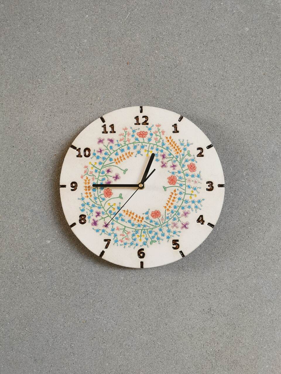 Niebieski wianek pełen kwiatów takich jak niezapominajki, maki, chabry, kłosy zbóż i trzykwiatki ulepiony z gliny