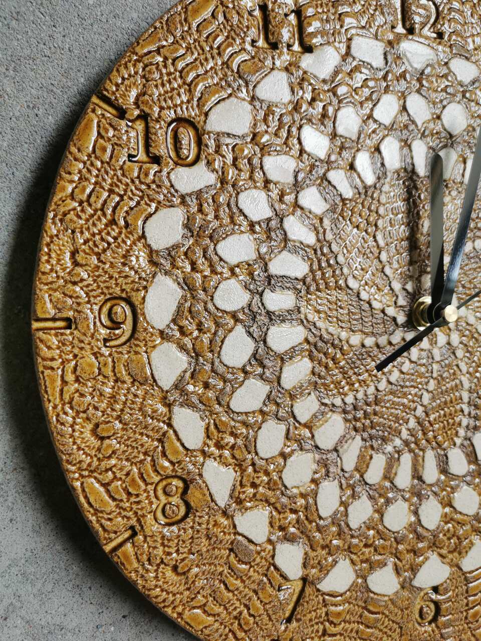 Profil ceramicznego zegara ściennego Eweolo. Widoczna organiczna forma tarczy w kolorach koniaku i naturalnej gliny oraz minimalistyczne wskazówki.
