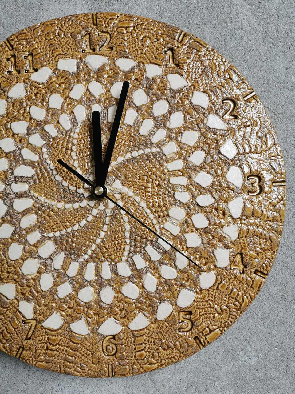 Zbliżenie na dwukolorowe szkliwienie zegara ceramicznego. Ciepły koniakowy odcień łączy się z przezroczystym szkliwem, ukazując fakturę jasnej gliny rzemieślniczej.