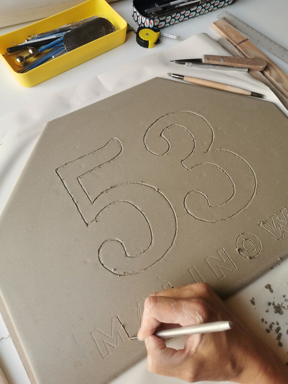 Dłubanie numeru na dom nazwy ulicy towrząc ręcznie ceramiczny szyld na elewację