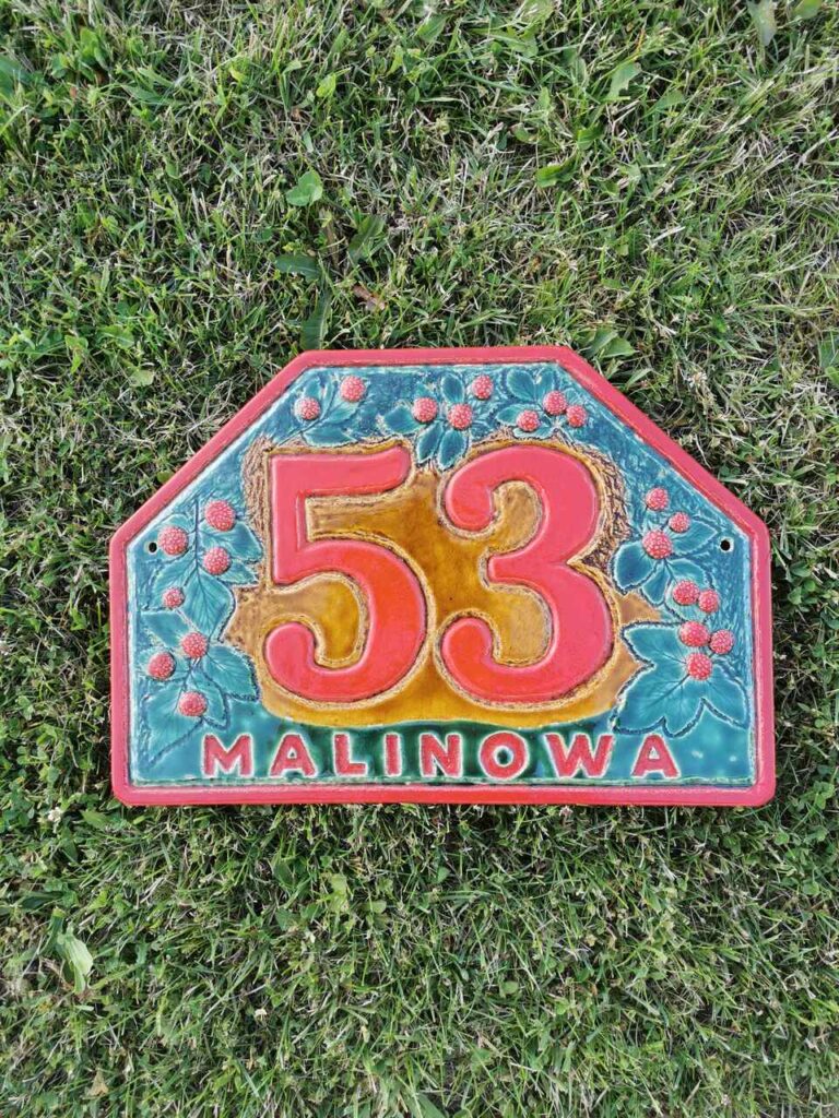 Malinowa ulica ceramiczny numer domu w trawie.