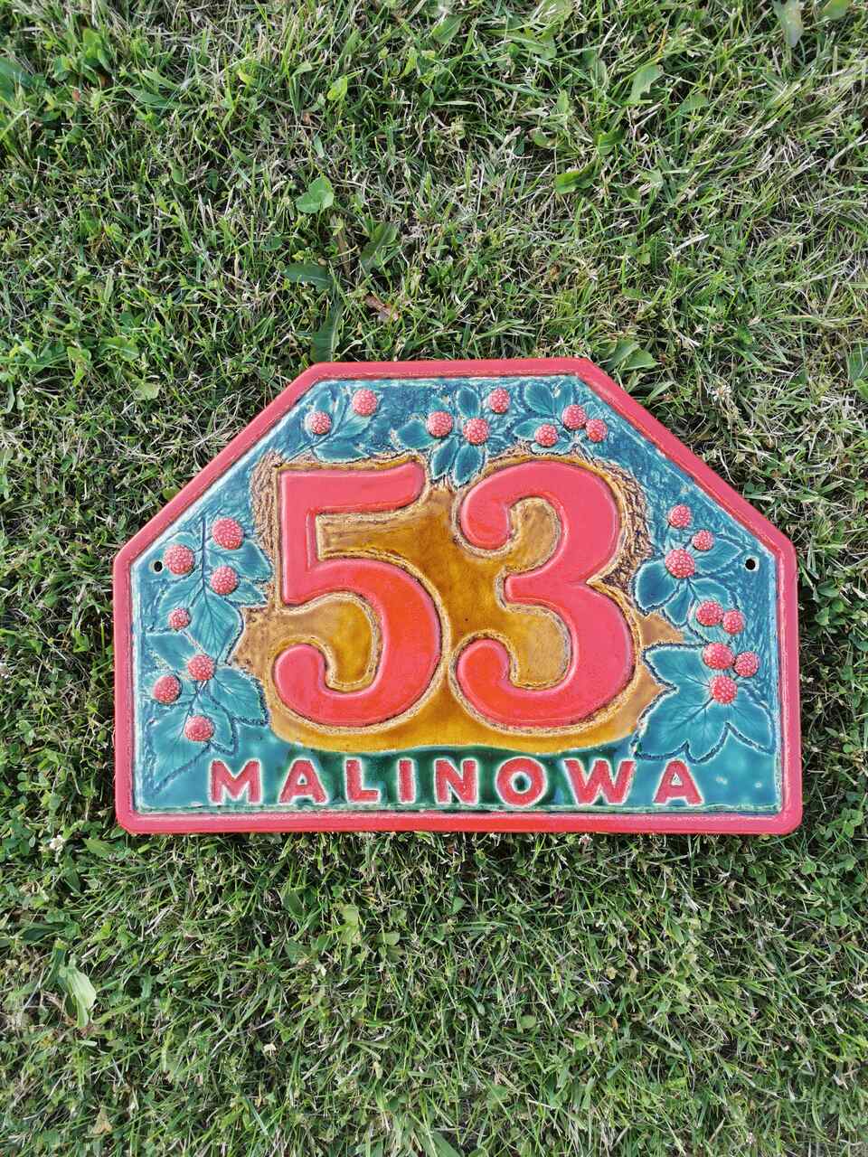 Malinowa ulica ceramiczny numer domu w trawie.