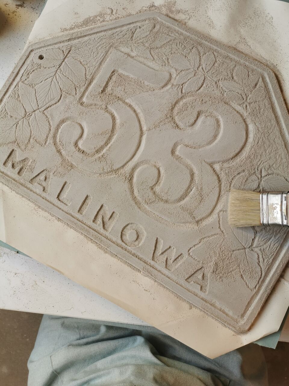 Przygotowywanie tabliczki adresowej do wypału w piecu ceramicznym.