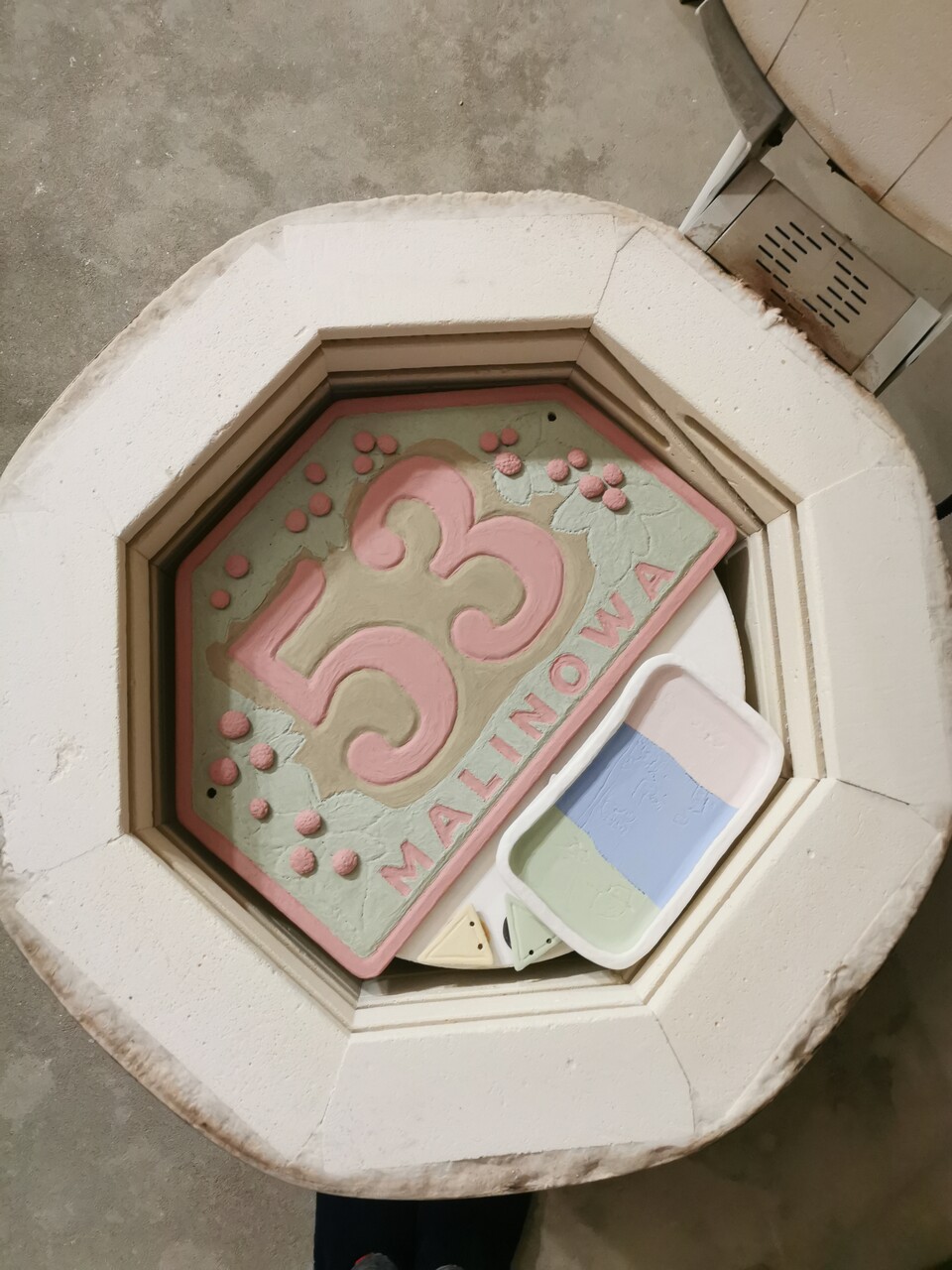Tablica adresowa z nałożonym ręcznie szkliwem przed wypałem w piecu ceramicznym.