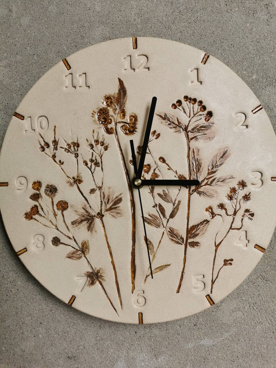 Ceramiczny ręcznie wykonany zegar z roślinami w kolorach ziemi.